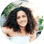 Person with curly hair smiling outdoors.